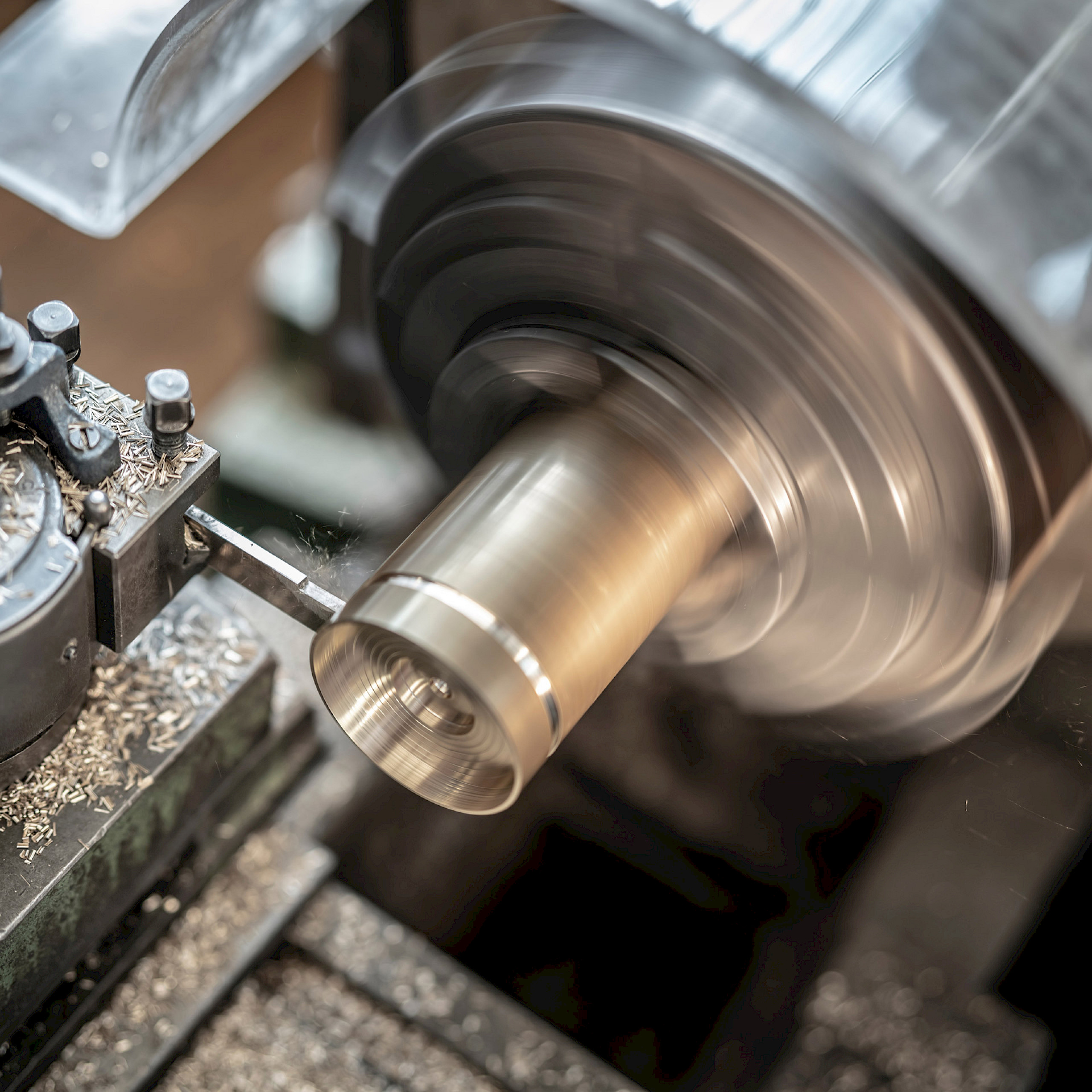 Eine Drehmaschine bearbeitet ein Metallstück. Metallschrott entsteht, während der Drehprozess abläuft.